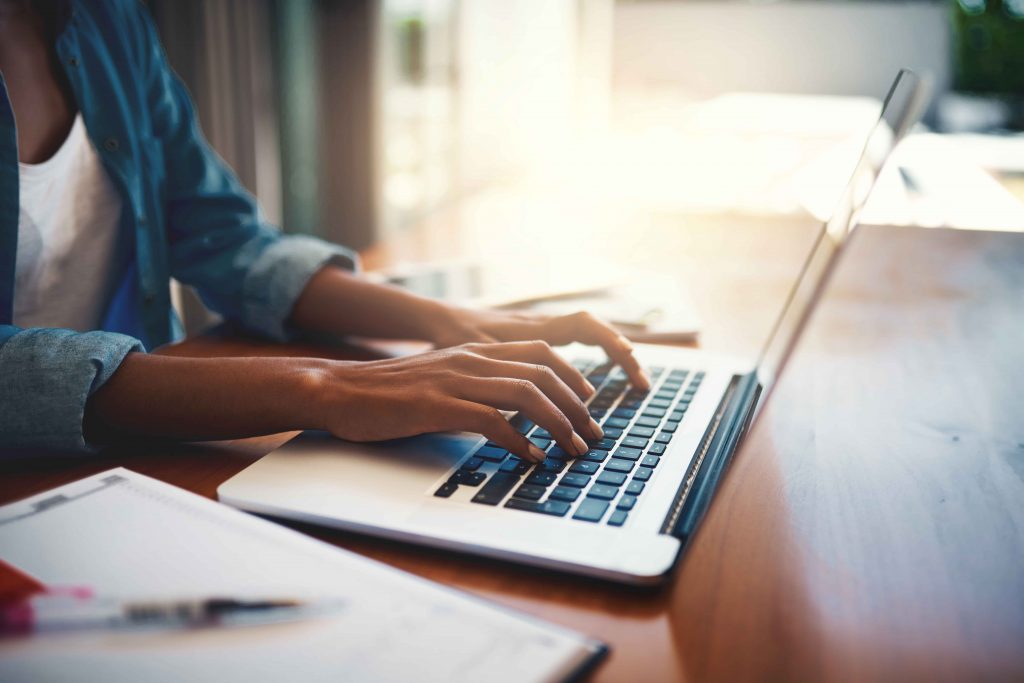Close up photo of a woman's hands typing on a MacBook keyboard